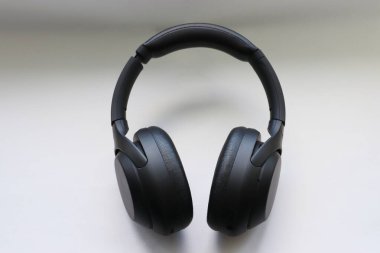 Beyaz zemin üzerinde modern siyah kablosuz kulaklıklar hareketliliğin ve teknolojik seçimin sembolü olarak