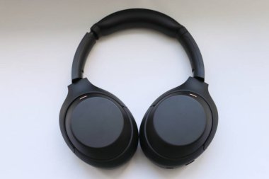 Beyaz zemin üzerinde modern siyah kablosuz kulaklıklar hareketliliğin ve teknolojik seçimin sembolü olarak