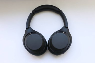 Beyaz zemin üzerinde modern siyah kablosuz kulaklıklar hareketliliğin ve teknolojik seçimin sembolü olarak