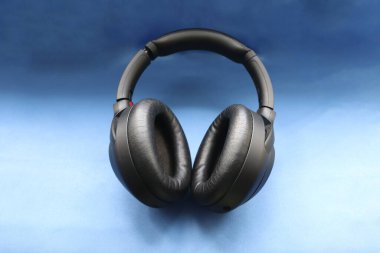 mavi arka planda modern siyah kablosuz kulaklıklar hareketliliğin ve teknolojik seçimin sembolü olarak