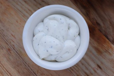 Seramik bir kasede bulunan kremalı Dorblu peynir sosu, ahşap bir arka planda, prim ve restoran tarzı tarifler için ideal bir malzeme.