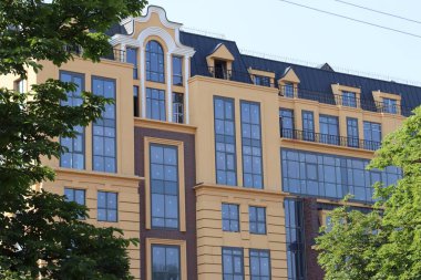 Geniş panoramik pencereleri, dekoratif cephesi ve şehir ortamında balkonları olan çok katlı modern bir bina.