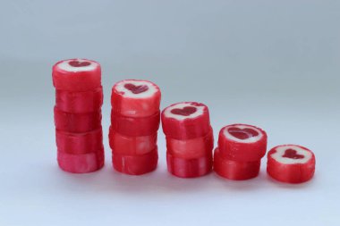 Kırmızı kalpli romantik şekerler, beyaz arka plan konsepti üzerine kurulmuş tatlı sembolizm, hediye dekorasyonu ve Sevgililer Günü için festival havası.