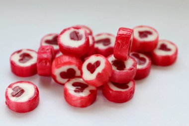 Beyaz arka planda kırmızı kalp şekilli şekerler romantik sembolizmin yakın plan konsepti, Sevgililer Günü için tatlı ruh hali ve hediye estetiği.