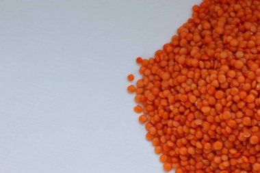 Beyaz zemin üzerine dağılmış kırmızı mercimekler doğal bitki temelli protein, sağlıklı beslenme ve minimalist gıda tasarımı konsepti