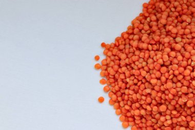 Beyaz zemin üzerine dağılmış kırmızı mercimekler doğal bitki temelli protein, sağlıklı beslenme ve minimalist gıda tasarımı konsepti