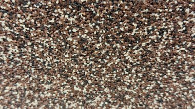 Çok renkli granüllerle dekoratif bir yüzeye yakın çekim. Kahverengi, beyaz ve siyah çakıl taşları içeren kaba doku..