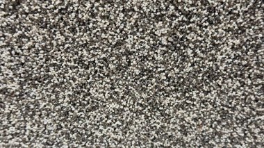 Ağırlıklı olarak siyah ve kahverengi parçacıklardan oluşan tanecikli bir yüzeye yakın çekim aşındırıcı madde, kum ya da çakıl gibi kaba bir doku..