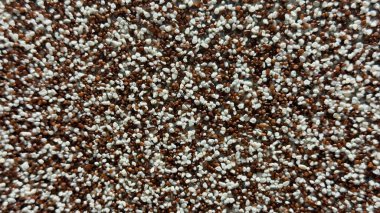 Beyaz ve kahverengi benekli, çakıl, tohum ya da tarımsal karışımı andıran doğal deseni olan tanecikli bir yüzeye yakın çekim.