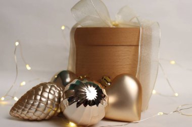 Beyaz arka planda altın Noel oyuncakları bulunan şenlikli ahşap hediye kutusu kış reklam kampanyaları, ambalaj tasarımı, e-ticaret, sosyal medya, kartpostallar ve afişler için çok yönlü bir resim.