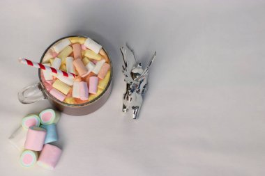 Renkli marşmelovlu sıcak kakao fincanı ve süslü çizgili kamışın yanında, kış reklamları için mükemmel bir tatil fotoğrafı, Noel kartları, kahve menüleri ve rahat yaşam tarzı içeriği.