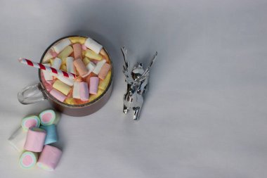 Renkli marşmelovlu sıcak kakao fincanı ve süslü çizgili kamışın yanında, kış reklamları için mükemmel bir tatil fotoğrafı, Noel kartları, kahve menüleri ve rahat yaşam tarzı içeriği.