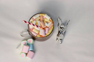 Renkli marşmelovlu sıcak kakao fincanı ve süslü çizgili kamışın yanında, kış reklamları için mükemmel bir tatil fotoğrafı, Noel kartları, kahve menüleri ve rahat yaşam tarzı içeriği.