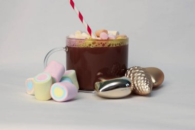 Kışın reklam kampanyaları, kafe menüleri, Noel tebrik kartları ve sosyal medya içeriği için kalp ve çam kozalağı şenliği fotoğrafı şeklinde altın Noel süslerinin yanında kırmızı ve beyaz pipetli sıcak kakao.