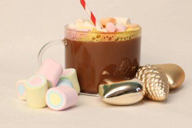 Kışın reklam kampanyaları, kafe menüleri, Noel tebrik kartları ve sosyal medya içeriği için kalp ve çam kozalağı şenliği fotoğrafı şeklinde altın Noel süslerinin yanında kırmızı ve beyaz pipetli sıcak kakao.