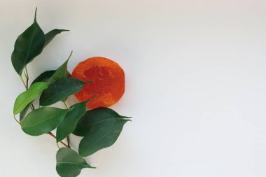 Doğal denge taze yeşil yapraklar ve beyaz arka planda parlak turuncu el yapımı sabun.