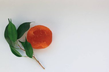 Doğal denge taze yeşil yapraklar ve beyaz arka planda parlak turuncu el yapımı sabun.