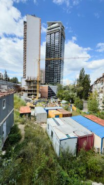 Ön planda kule vinci ve geçici konteynırları olan modern yüksek binaların inşaat alanı