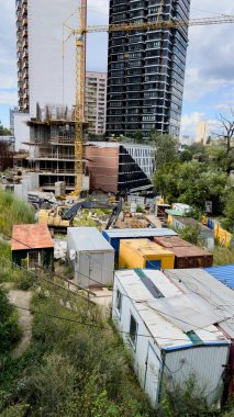 Ön planda kule vinci ve geçici konteynırları olan modern yüksek binaların inşaat alanı