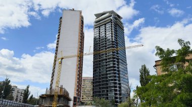 Ön planda kule vinci ve geçici konteynırları olan modern yüksek binaların inşaat alanı