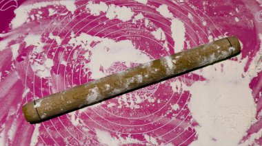 Pembe silikon bir paspasın üzerinde klasik ahşap bir raptiye üzerinde işaretler ve flüt konsepti serpiştirilmiş ev yapımı, aşçılık süreci ve mutfak aletleri..