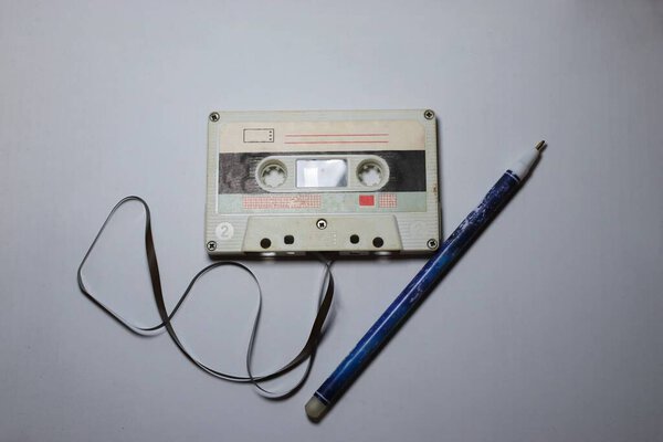 A vintage audio cassette with an extended tape and a handle  a symbol of nostalgia, analog aesthetics, and manual rewinding in the style of the 80s and 90s.