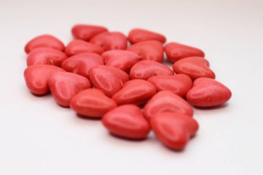 Red glossy heart-shaped candies on a white background  a decorative accent for romantic designs, festive projects, and food content.