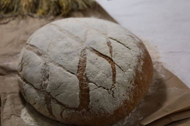 Kahverengi bir kağıt ve mısırın üzerinde un olan taze pişmiş bir ekmek. Yüksek kalite fotoğraf