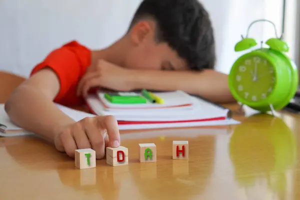 stock image child surrounded by books and notebooks frustrated, with the acronym TDAH spanish acronym for  ADHD, represents the disease Attention Deficit Disorder and the difficulties it entails in school life.