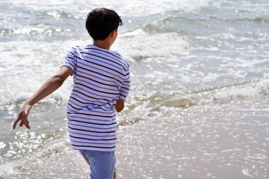 Yazın deniz kıyısında koşan çocuk