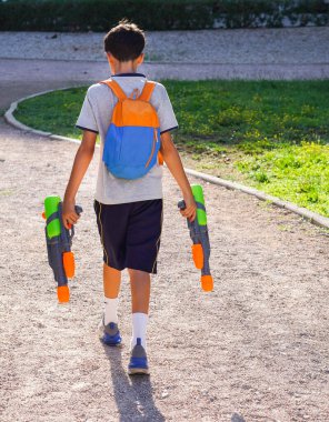 Parkta su tabancaları olan, sırtı dönük bir çocuk.