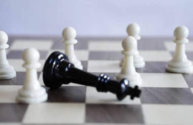 Satranç kralını çevreleyen birkaç satranç piyonu.