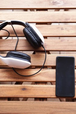 Kulaklık ve akıllı telefon ahşap teras masasında.