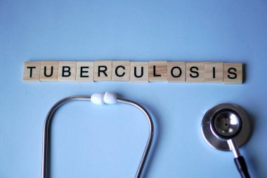 TUBERCULOSIS, ahşap harfler ve yumuşak mavi arka planlı steteskop.