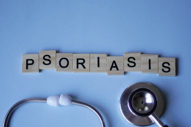 PSORIASIS, ahşap bloklar ve açık mavi arka planda steteskop. tıp konsepti