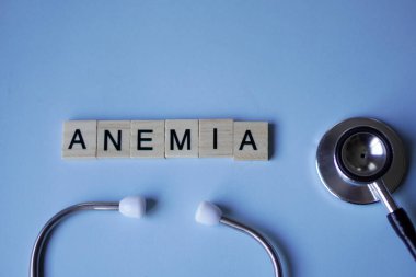 ANEMIA, harfli tahta bloklar ve açık mavi arka planlı steteskop. tıp konsepti