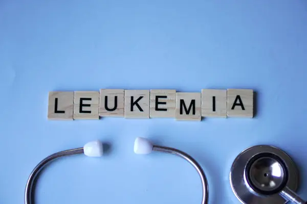 LEUKEMIA, harfli ahşap bloklar ve açık mavi arka planlı steteskop. tıp konsepti