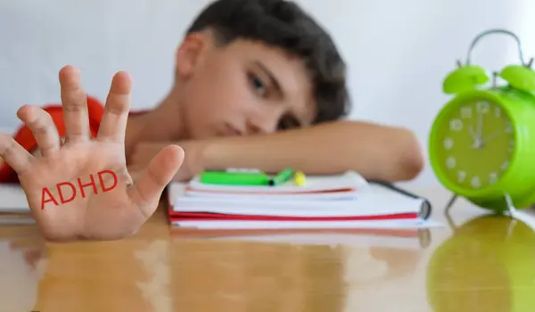 Stock image ADHD, Attention Deficit Disorder, child's palm with books and notebooks and gesture of concern and sadness