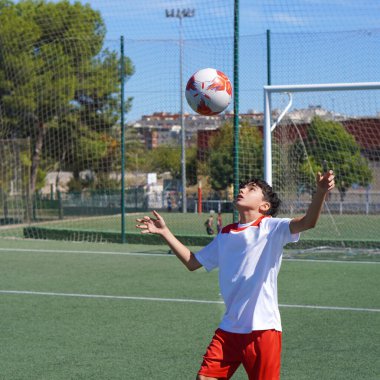 Genç çocuk futbol sahasında kafa tokuşturma antrenmanı yapıyor.