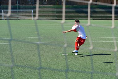 topu arka planda tekmeleyen oyuncu ile gol ağı