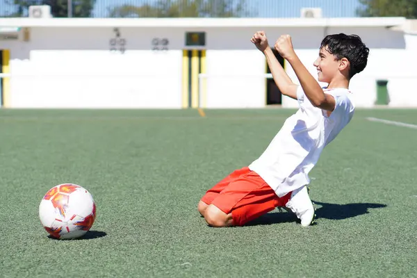 Genç bir çocuk futbol maçında bir gol ya da zaferi kutluyor.