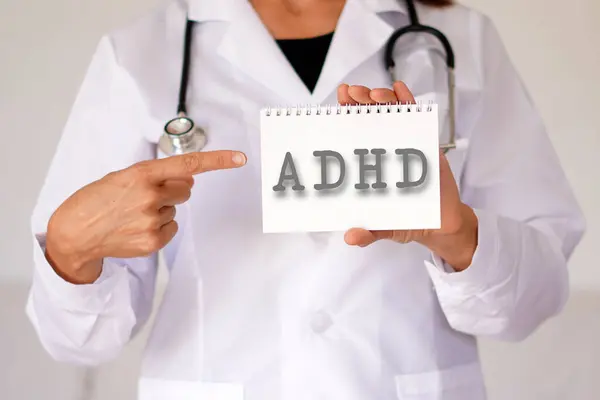 Kadın, doktor bir not defterine ADHD kısaltması dikkat eksikliği bozukluğu.