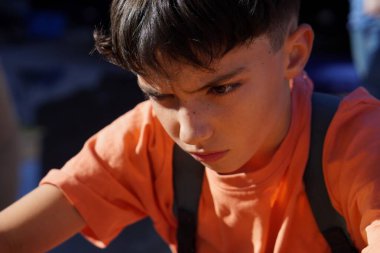 Sırt çantalı ergen çocuk, okuldan çıkarken endişeli ve üzgün görünüyor.