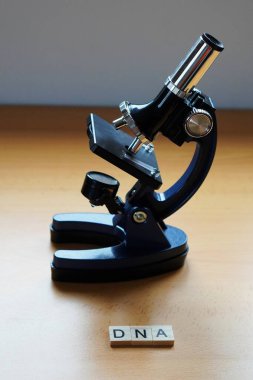 DNA konsepti. Tahta bir masanın üzerinde mikroskop olan ahşap harfler. ilaç kavramları