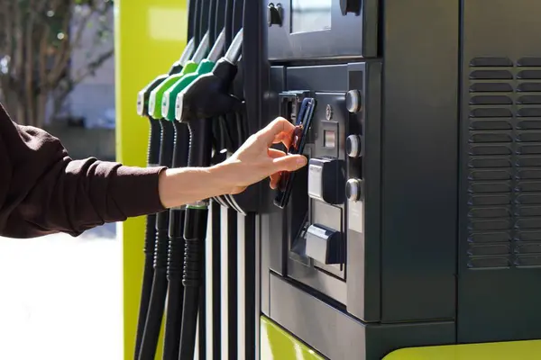 Benzin istasyonundaki kadın cep telefonunu pompaya dayayıp uygulamasının indirimlerini yapıyor.