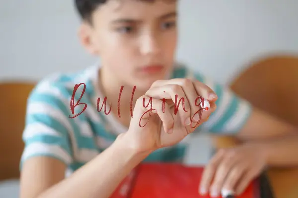 Zorbalık konsepti. Telaşlı genç çocuk ekrana kelime yazıyor..