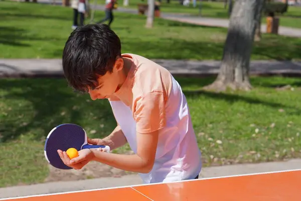 Genç çocuklar ve spor. Açık hava aktiviteleri. Masa tenisi, parkta pratik yapan çocuk..