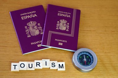 Turizm konsepti. İki İspanyol pasaportu ve bir pusula ile birlikte ahşap harfler..