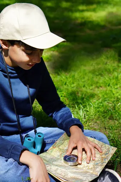 seyahat ve tatil. Açık hava aktiviteleri. Haritası, pusulası ve dürbünü olan bir çocuk..