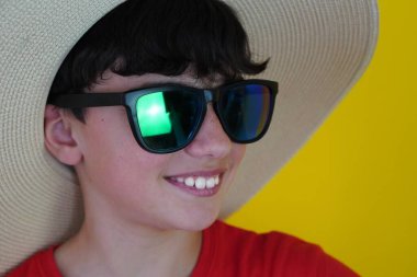 Tatil ve seyahat. sarı arkaplan ve kırmızı tişörtlü, şapka ve güneş gözlüklü çocuk..